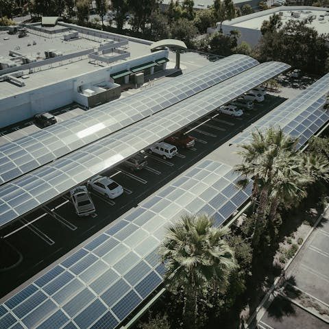 Gewerbliche Parkflächen mit Solarpanelen auf Dächern und umgeben von Palmen.